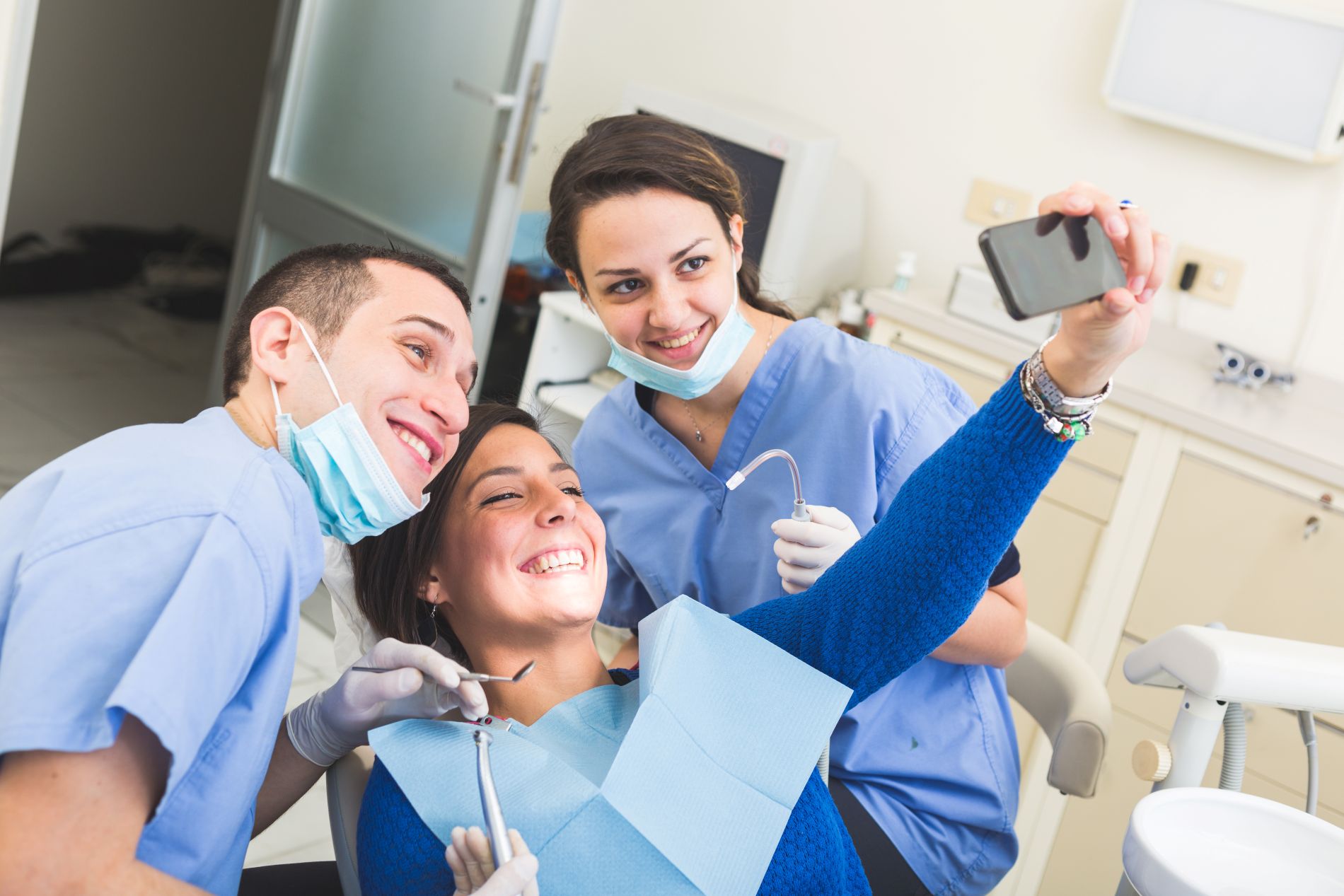 Lächelnde Patientin und Behandler nach einer Professionellen Zahnreinigung nehmen ein Selfie auf.